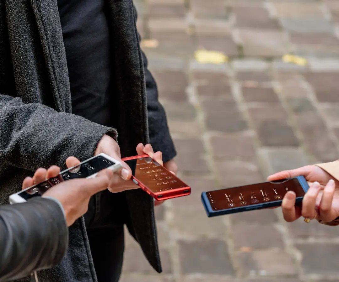 Трима приятели щастливо държат преводачите си, участват в разговори и споделят моменти заедно. 