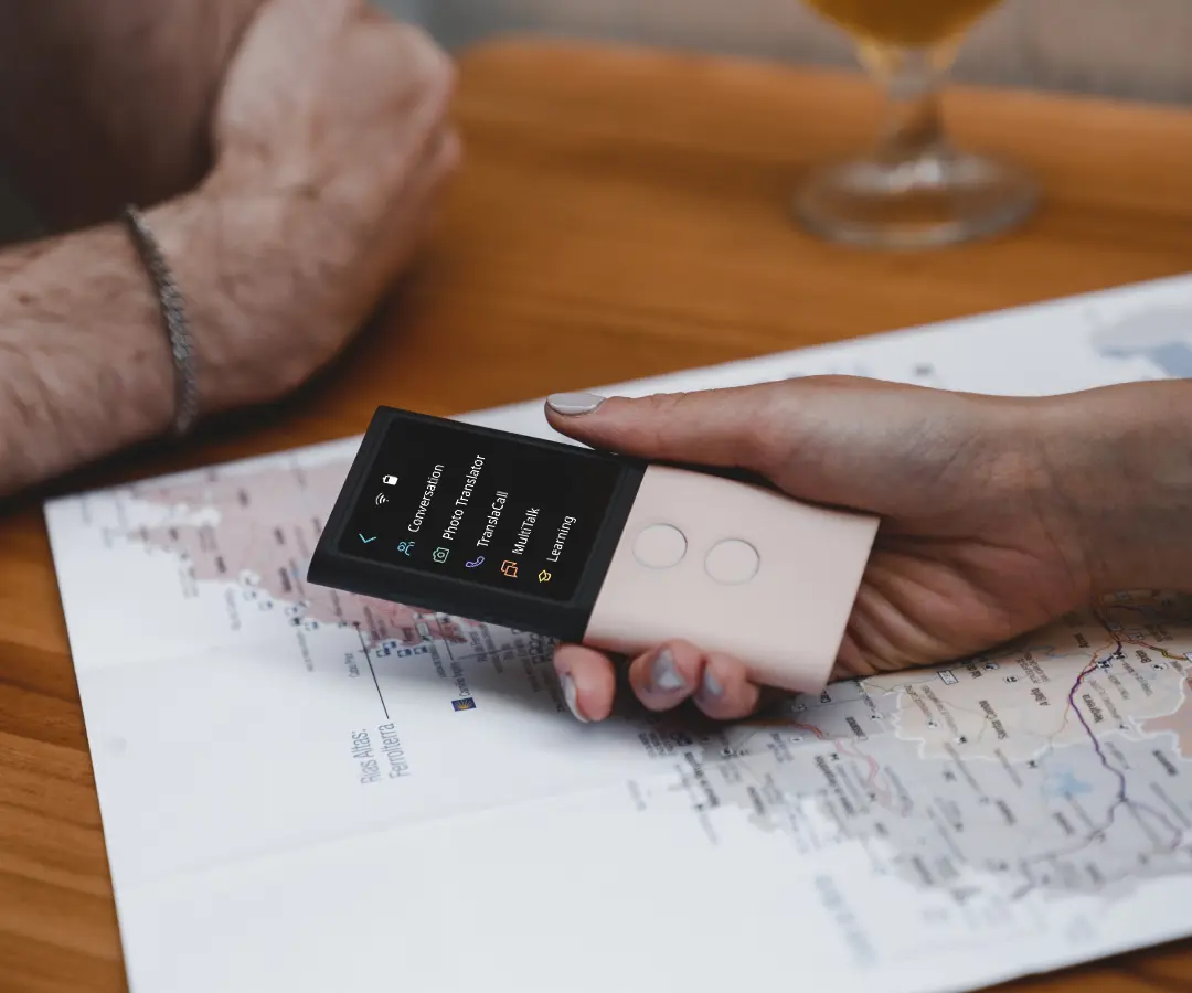 Близък план на ръка, която държи преводач над маса с карта върху нея